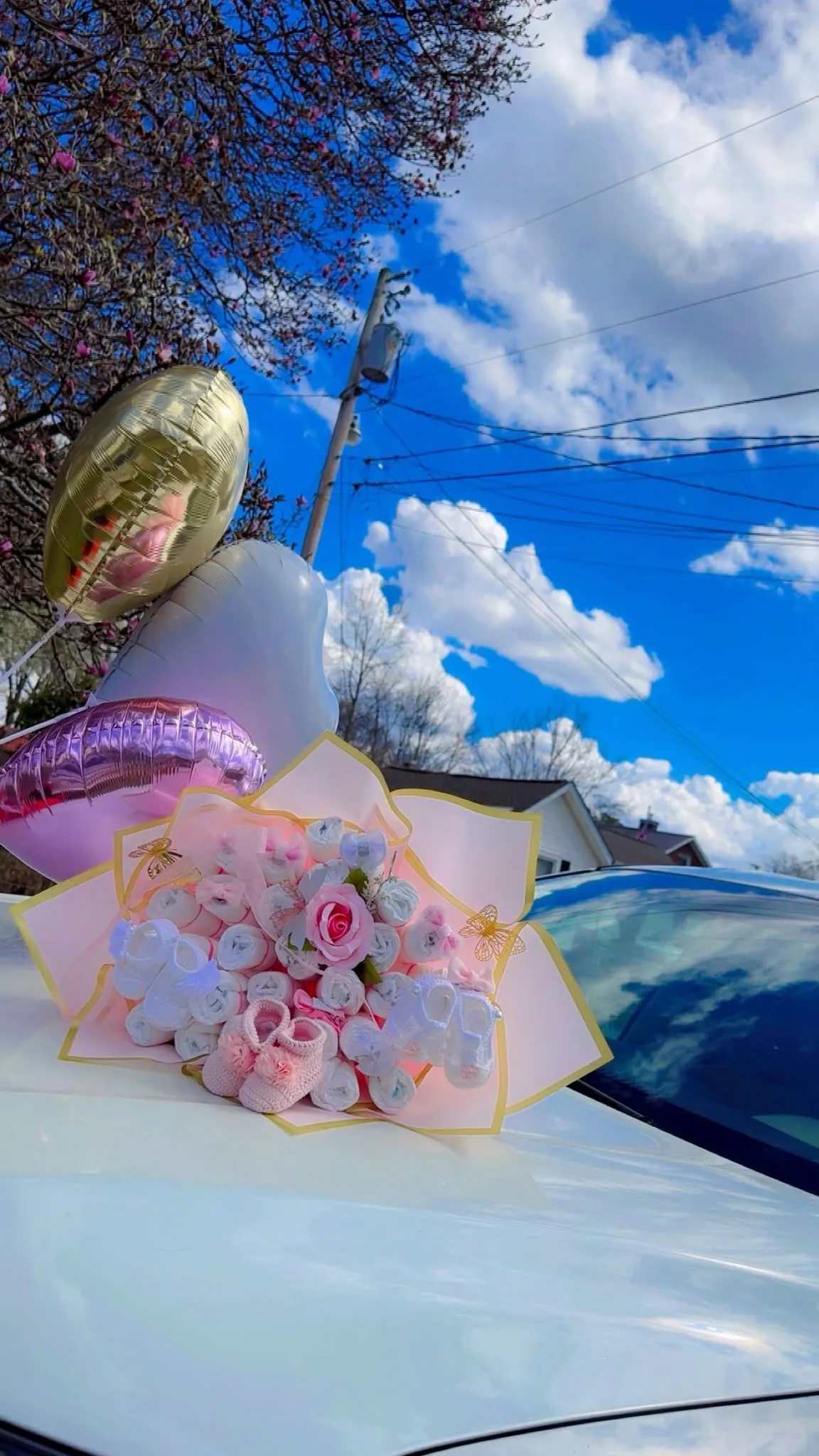 Ramo de flores rosas y blancas con globos sobre un auto blanco