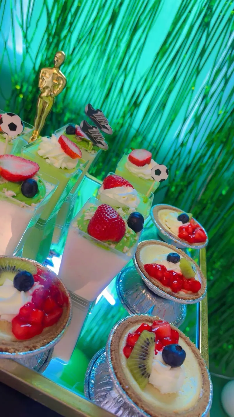 Copas de postre con fresas y kiwi frente a una cortina verde