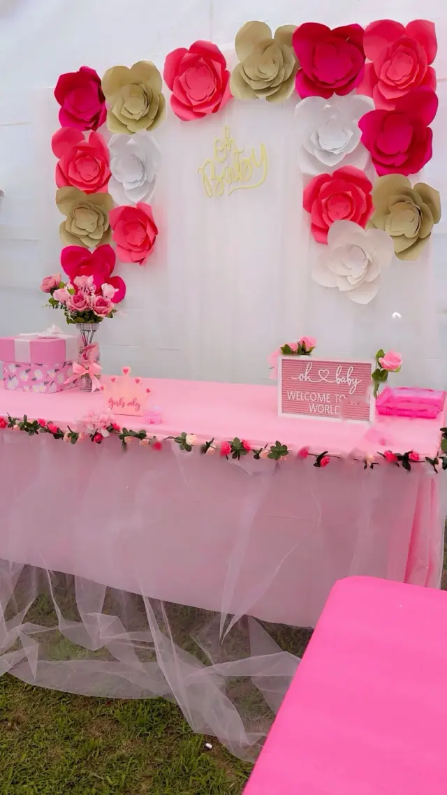 Mesa rosa con tul y un fondo de flores de papel