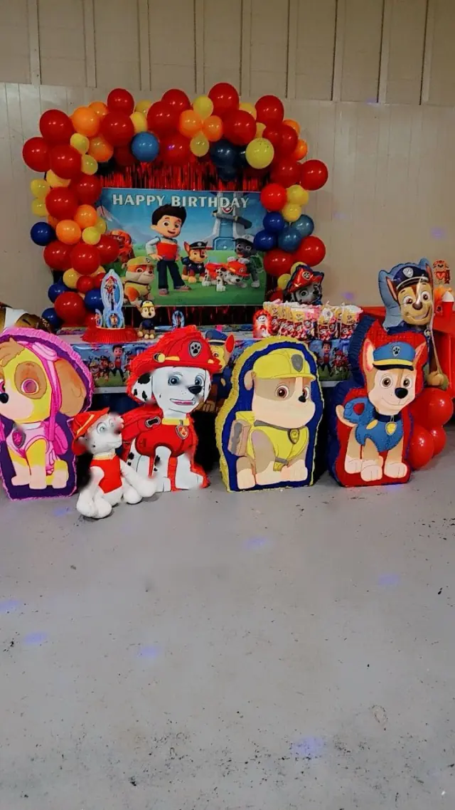Mesa de cumpleaños con arco de globos de colores y figuras de personajes