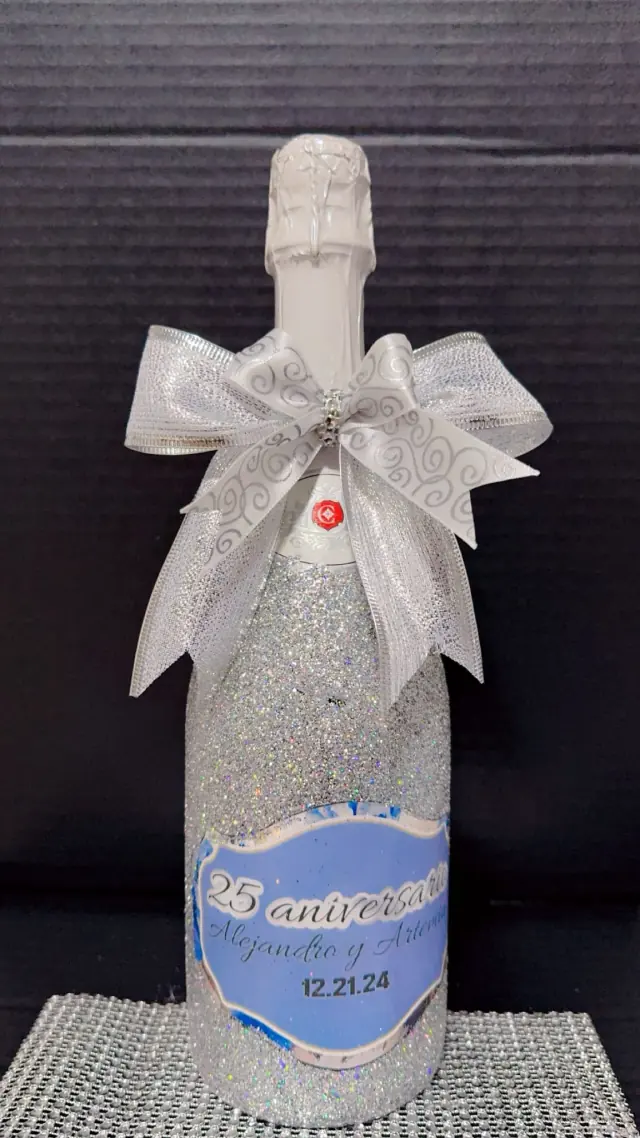 Botella decorada con brillo plateado, moño y etiqueta personalizada