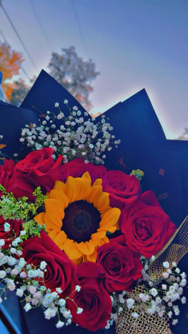 Ramo de rosas rojas con un girasol al centro